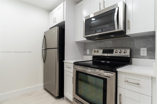 13255 SW 7th Ct Unit 303D, Pembroke Pines, FL 33027 - kitchen with appliances with stainless steel finishes, backsplash, white cabinets, and light wood finished floors
