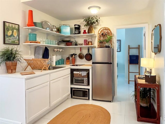 335 Ocean Dr Unit 114, Miami Beach, FL 33139 - kitchen with stainless steel appliances, light tile patterned flooring, light countertops, and white cabinets