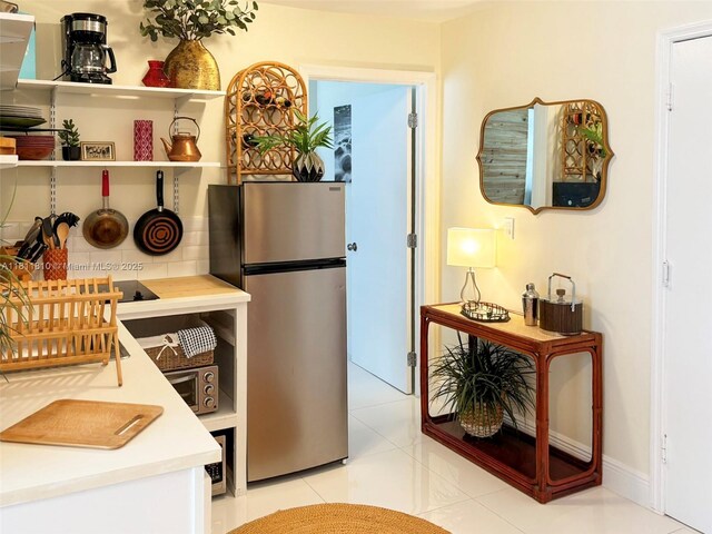 335 Ocean Dr Unit 114, Miami Beach, FL 33139 - kitchen featuring freestanding refrigerator, light countertops, light tile patterned floors, and baseboards