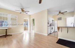 1416 N 2nd Ave N, Lake Worth, FL 33460 - unfurnished living room featuring a ceiling fan, wood finished floors, baseboards, and a sink