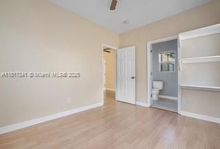 1416 N 2nd Ave N, Lake Worth, FL 33460 - unfurnished bedroom featuring wood finished floors, baseboards, ensuite bathroom, and ceiling fan