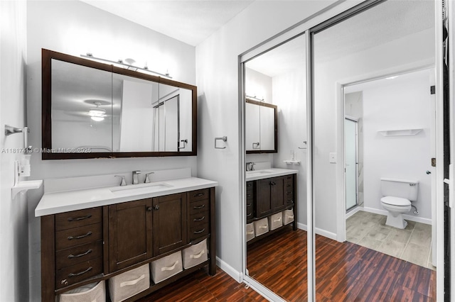 16040 SW 287th St, Homestead, FL 33033 - full bath with wood finished floors, a shower stall, two vanities, toilet, and baseboards