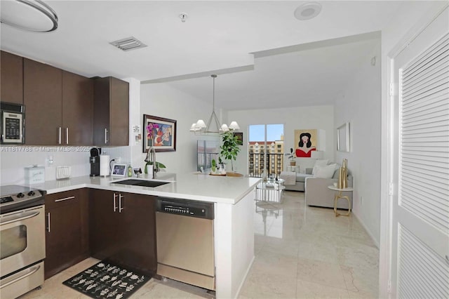 10 Aragon Ave Unit 919, Coral Gables, FL 33134 - kitchen with stainless steel appliances, a sink, light countertops, dark brown cabinetry, and a peninsula