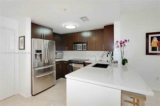 10 Aragon Ave Unit 919, Coral Gables, FL 33134 - kitchen featuring stainless steel appliances, a sink, light countertops, dark brown cabinetry, and a peninsula