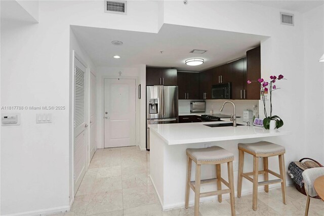 10 Aragon Ave Unit 919, Coral Gables, FL 33134 - kitchen featuring stainless steel fridge, black microwave, a peninsula, a breakfast bar area, and a sink