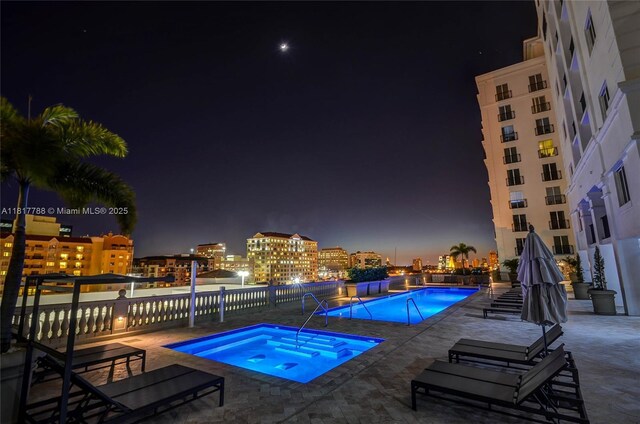 10 Aragon Ave Unit 919, Coral Gables, FL 33134 - pool at night with a hot tub, a community pool, a patio area, and a view of city lights