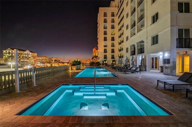 10 Aragon Ave Unit 919, Coral Gables, FL 33134 - pool at twilight featuring a community pool, a community hot tub, and a patio area