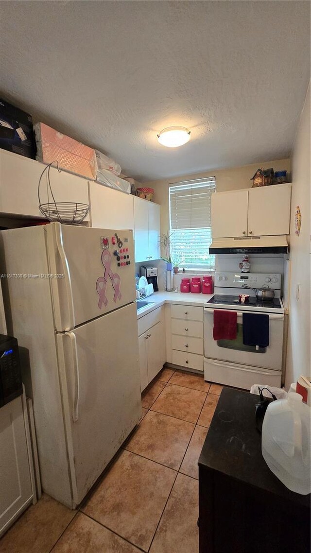 13655 NE 10th Ave Unit 108, North Miami, FL 33161 - kitchen with white appliances, under cabinet range hood, white cabinetry, light tile patterned floors, and a textured ceiling