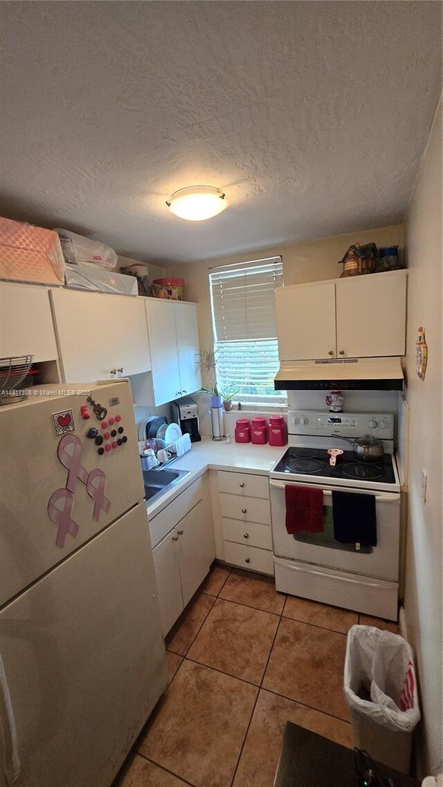 13655 NE 10th Ave Unit 108, North Miami, FL 33161 - kitchen with white appliances, white cabinets, light tile patterned flooring, light countertops, and a textured ceiling