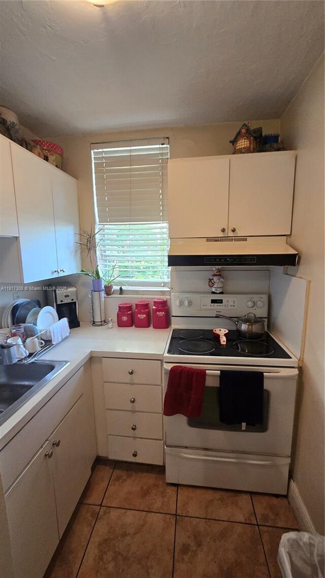 13655 NE 10th Ave Unit 108, North Miami, FL 33161 - kitchen featuring white electric range oven, under cabinet range hood, a sink, light countertops, and tile patterned flooring