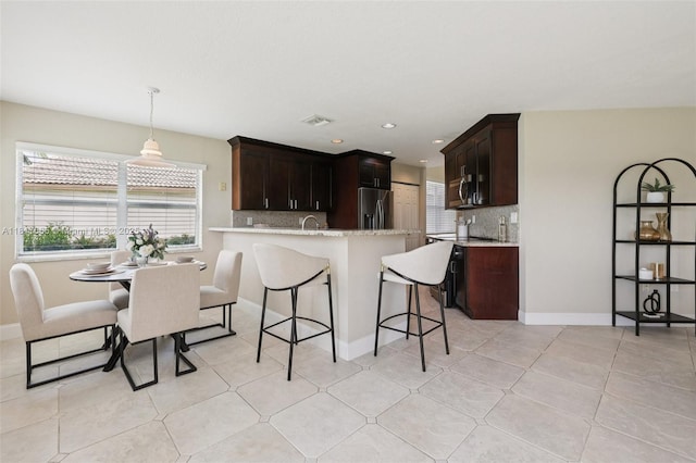 16710 NW 12th St, Pembroke Pines, FL 33028 - kitchen featuring appliances with stainless steel finishes, decorative backsplash, a kitchen breakfast bar, a peninsula, and dark brown cabinetry