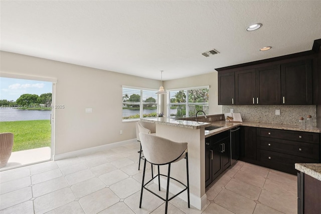 16710 NW 12th St, Pembroke Pines, FL 33028 - kitchen featuring tasteful backsplash, a water view, a peninsula, a textured ceiling, and a kitchen breakfast bar
