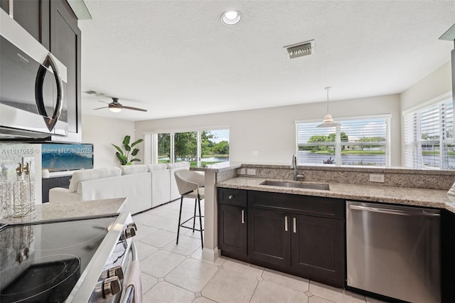 16710 NW 12th St, Pembroke Pines, FL 33028 - kitchen featuring stainless steel appliances, healthy amount of natural light, ceiling fan, light stone countertops, and a textured ceiling
