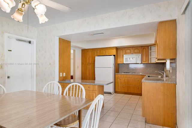 8980 SW 59th St, Miami, FL 33173 - kitchen with white appliances, wallpapered walls, decorative backsplash, light tile patterned floors, and brown cabinets