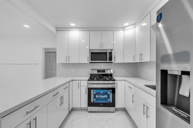 1010 NE 140th St, North Miami, FL 33161 - kitchen featuring stainless steel appliances, recessed lighting, white cabinetry, light marble finish floors, and tasteful backsplash