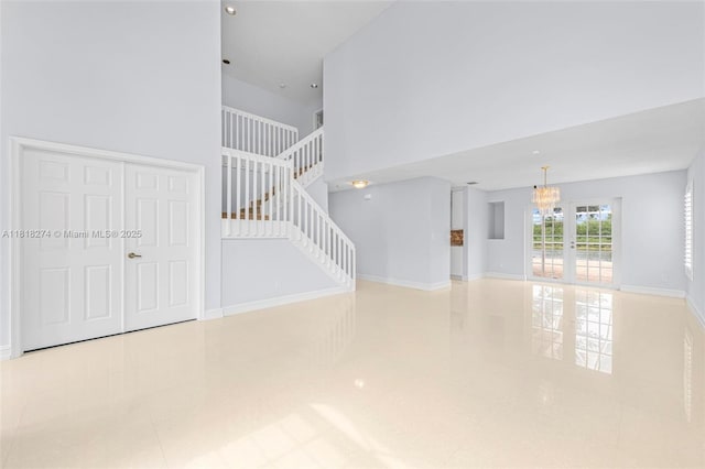 2256 SW 183rd Ter, Miramar, FL 33029 - unfurnished living room featuring a chandelier, tile patterned flooring, a towering ceiling, stairway, and baseboards