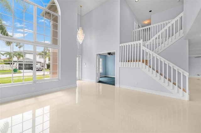 2256 SW 183rd Ter, Miramar, FL 33029 - unfurnished living room with a towering ceiling, ceiling fan, stairway, baseboards, and tile patterned floors