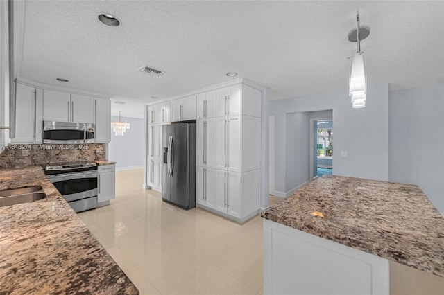 2256 SW 183rd Ter, Miramar, FL 33029 - kitchen with stainless steel appliances, a textured ceiling, white cabinets, stone countertops, and a chandelier