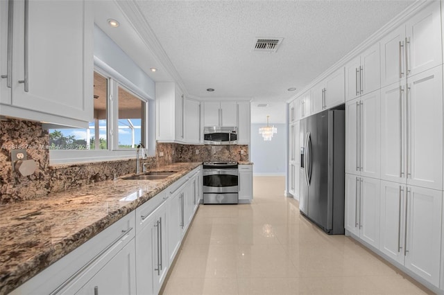 2256 SW 183rd Ter, Miramar, FL 33029 - kitchen featuring stainless steel appliances, a sink, white cabinets, a textured ceiling, and decorative backsplash