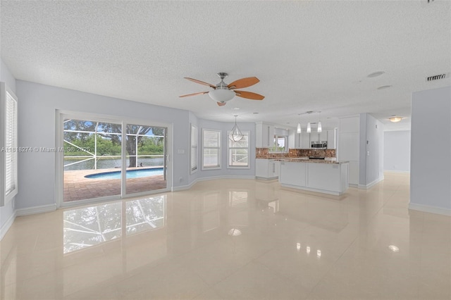 2256 SW 183rd Ter, Miramar, FL 33029 - unfurnished living room featuring baseboards, a textured ceiling, a ceiling fan, and light tile patterned floors