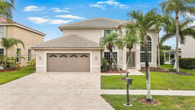 2256 SW 183rd Ter, Miramar, FL 33029 - mediterranean / spanish house with a tile roof, stucco siding, an attached garage, a front yard, and decorative driveway