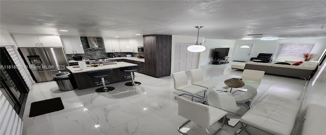 11820 SW 125th Pl Unit 11820, Miami, FL 33186 - kitchen featuring stainless steel appliances, a kitchen breakfast bar, decorative backsplash, light countertops, and wall chimney range hood
