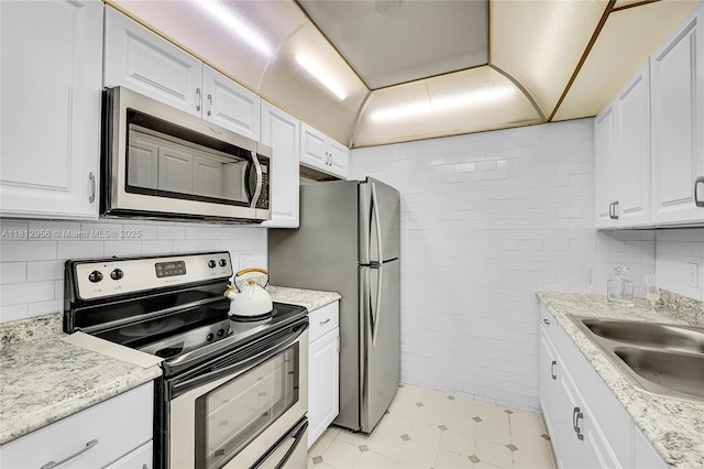 1551 SW 135th Ter Unit 112G, Pembroke Pines, FL 33027 - kitchen featuring stainless steel appliances, tile walls, white cabinetry, and light stone counters