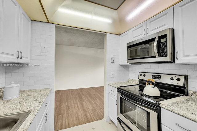 1551 SW 135th Ter Unit 112G, Pembroke Pines, FL 33027 - kitchen with stainless steel appliances, decorative backsplash, white cabinets, light stone countertops, and light wood finished floors