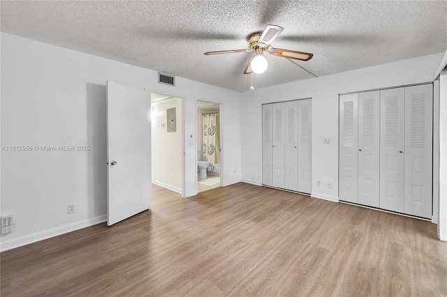 1551 SW 135th Ter Unit 112G, Pembroke Pines, FL 33027 - unfurnished bedroom with a textured ceiling, multiple closets, wood finished floors, ensuite bath, and a ceiling fan