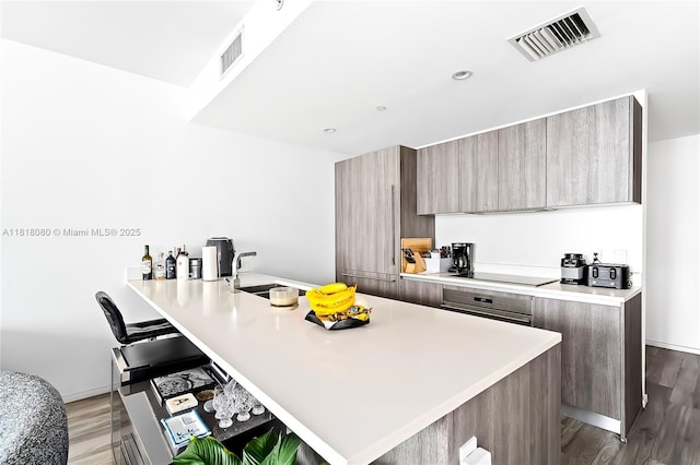 801 S Miami Ave Unit 3704, Miami, FL 33130 - kitchen featuring modern cabinets, light countertops, wood finished floors, a breakfast bar area, and a peninsula