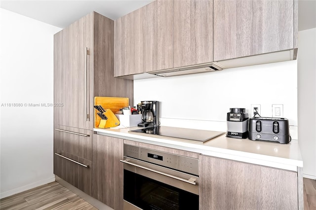 801 S Miami Ave Unit 3704, Miami, FL 33130 - kitchen featuring stainless steel oven, modern cabinets, black electric stovetop, light countertops, and light wood-style floors
