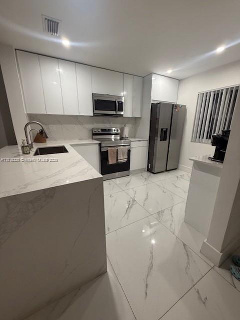 14085 SW 179th Ter, Miami, FL 33177 - kitchen with appliances with stainless steel finishes, light marble finish floors, modern cabinets, white cabinets, and recessed lighting