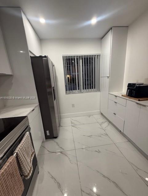 14085 SW 179th Ter, Miami, FL 33177 - kitchen with stainless steel range with electric cooktop, white cabinetry, freestanding refrigerator, light marble finish flooring, and modern cabinets