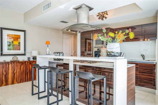 3737 Collins Ave Unit S-403, Miami Beach, FL 33140 - kitchen featuring a kitchen breakfast bar, modern cabinets, island exhaust hood, light tile patterned floors, and stainless steel gas stovetop