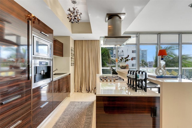 3737 Collins Ave Unit S-403, Miami Beach, FL 33140 - kitchen with modern cabinets, stainless steel appliances, island exhaust hood, a chandelier, and light countertops
