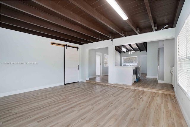 1025 SW 22nd Ter, Fort Lauderdale, FL 33312 - unfurnished living room with a barn door, beam ceiling, light wood finished floors, and healthy amount of natural light