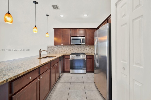 279 SE 31st Ter, Homestead, FL 33033 - kitchen featuring appliances with stainless steel finishes, light stone countertops, tasteful backsplash, light tile patterned flooring, and hanging light fixtures