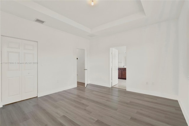 279 SE 31st Ter, Homestead, FL 33033 - unfurnished bedroom with wood finished floors, a tray ceiling, a closet, and connected bathroom