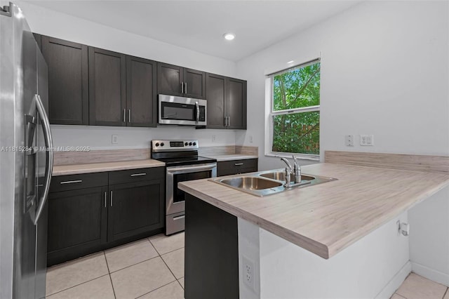 2652 SE 13th St, Homestead, FL 33035 - kitchen with appliances with stainless steel finishes, a sink, a peninsula, light tile patterned floors, and light countertops