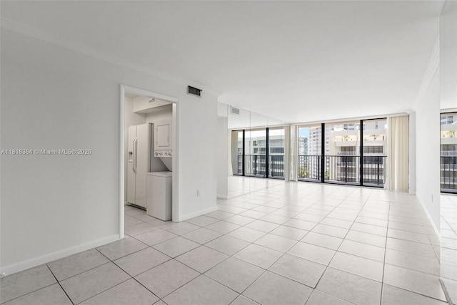 1450 Brickell Bay Dr Unit 806, Miami, FL 33131 - unfurnished room with stacked washing machine and dryer, ornamental molding, light tile patterned floors, baseboards, and a wall of windows