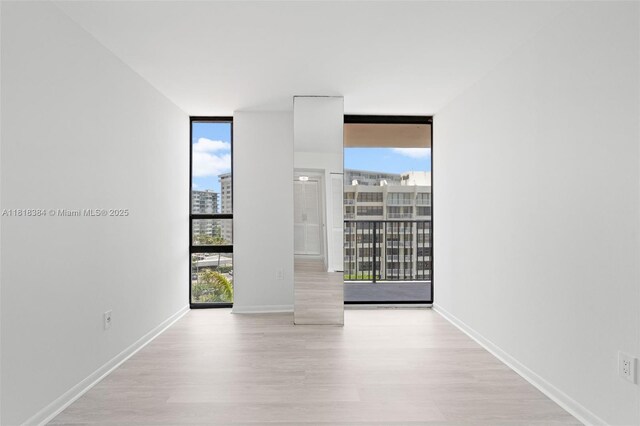 1450 Brickell Bay Dr Unit 806, Miami, FL 33131 - empty room with floor to ceiling windows, wood finished floors, a city view, and baseboards