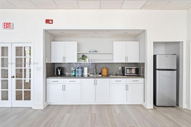1450 Brickell Bay Dr Unit 806, Miami, FL 33131 - kitchen featuring appliances with stainless steel finishes, a sink, light wood finished floors, and white cabinetry