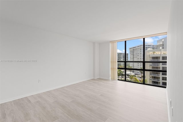 1450 Brickell Bay Dr Unit 806, Miami, FL 33131 - empty room with floor to ceiling windows, a city view, wood finished floors, and baseboards