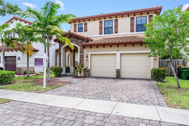 150 NE 23rd Ter, Homestead, FL 33033 - mediterranean / spanish home featuring stone siding, stucco siding, decorative driveway, a garage, and a tiled roof