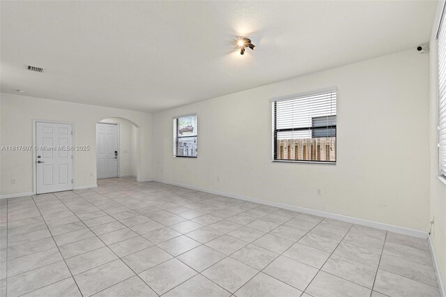 150 NE 23rd Ter, Homestead, FL 33033 - spare room with arched walkways, light tile patterned floors, and baseboards