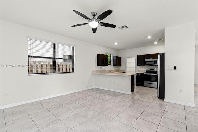 150 NE 23rd Ter, Homestead, FL 33033 - kitchen featuring appliances with stainless steel finishes, light countertops, a ceiling fan, light tile patterned flooring, and a peninsula