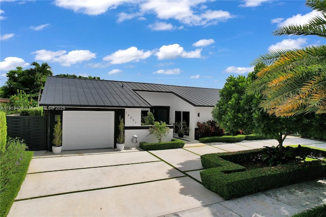 14051 SW 48th St, Miami, FL 33175 - view of front facade with a standing seam roof, an attached garage, stucco siding, driveway, and metal roof