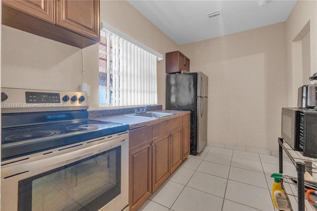1478 NW 74th St, Miami, FL 33147 - kitchen featuring stainless steel appliances, brown cabinets, light tile patterned flooring, and dark countertops