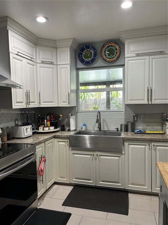 2320 SW 16th Ter, Miami, FL 33145 - kitchen with electric range, wall chimney range hood, backsplash, white cabinetry, and recessed lighting