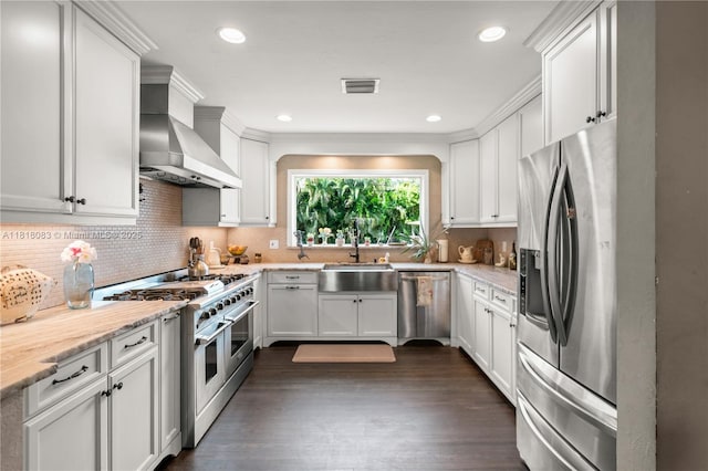 4240 SW 9th St, Plantation, FL 33317 - kitchen featuring stainless steel appliances, wall chimney exhaust hood, white cabinets, tasteful backsplash, and dark wood finished floors